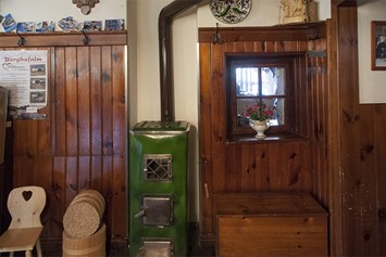 Restaurant: Der wohlig warme Holzofen für kalte Wintertage verbreitet Wohlbehagen und ladet zum Verweilen ein. - Gasthaus Buchegger