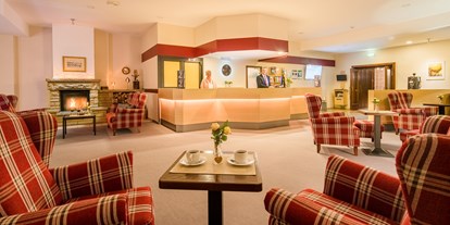 Essen-gehen - grüner Gastgarten - PLZ 34125 (Deutschland) - Hotellobby mit Rezeption, gemütlichem Sitzbereich und Kamin - Restaurants "Libelle" & "blaue Ente" im Waldhotel Schäferberg